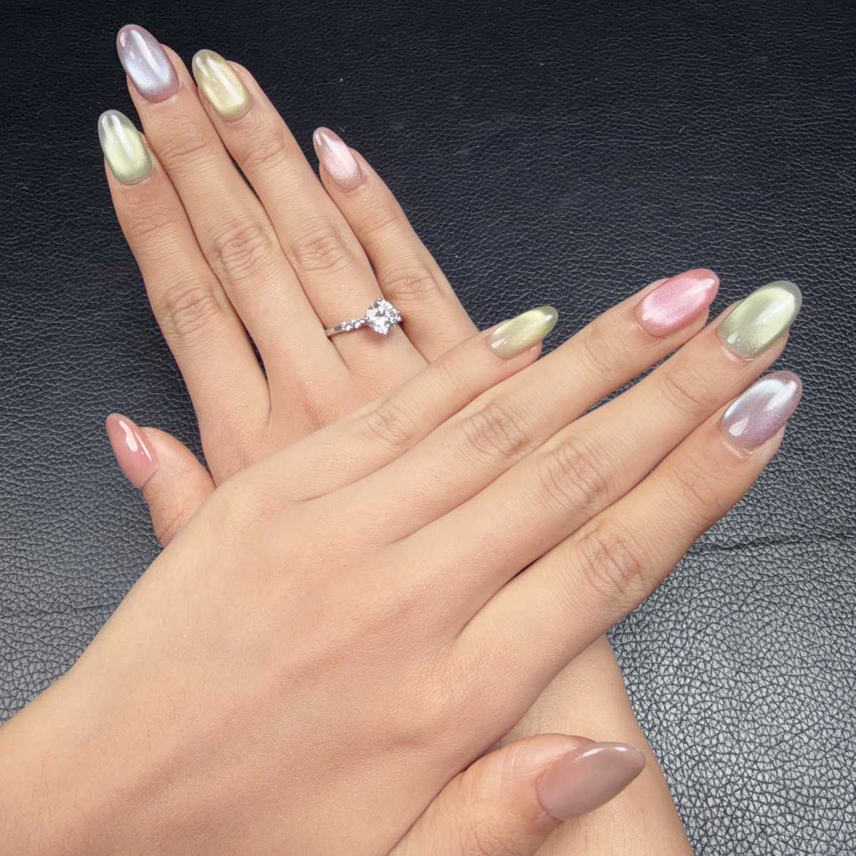 Hands wearing Multicolor cat eye oval press-on nails in pink, sage green, lavender and champagne