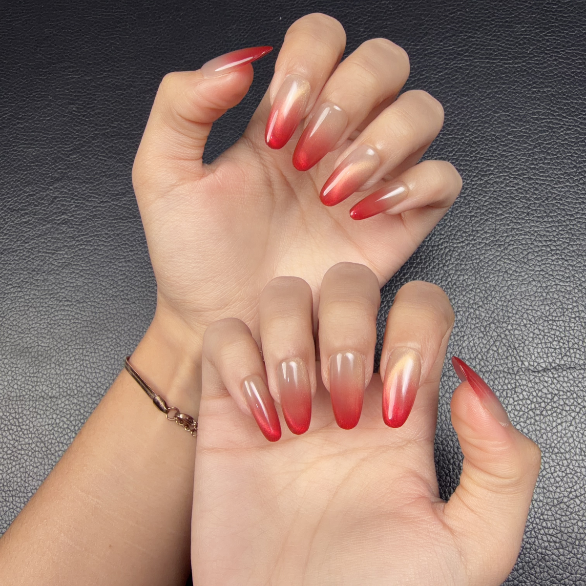 Hands wearing Ruby Fade red ombre golden cat eye press-on nails