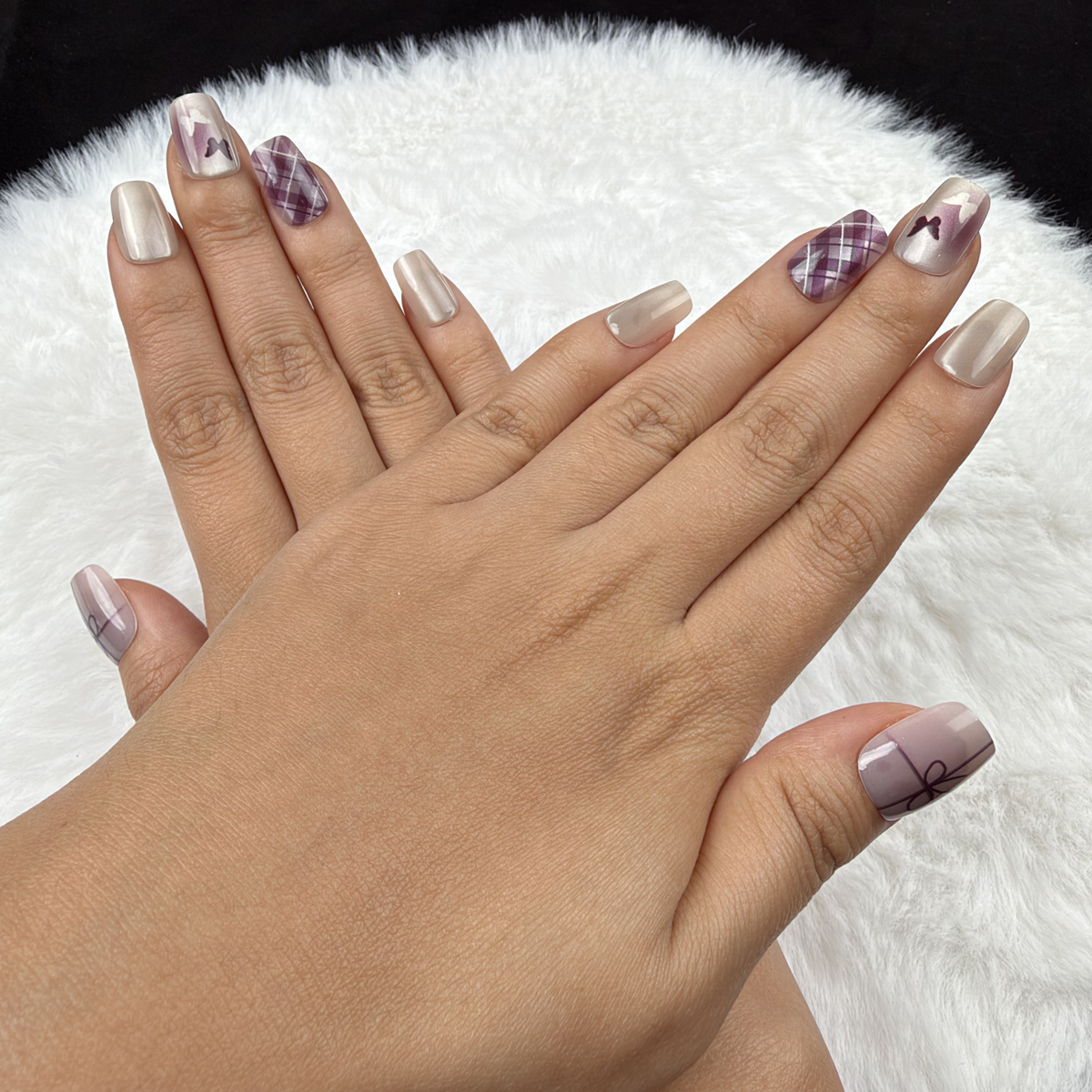 Detail shot of Ribbon Plaid pearl white and plum bow and plaid square press-on nails on hand