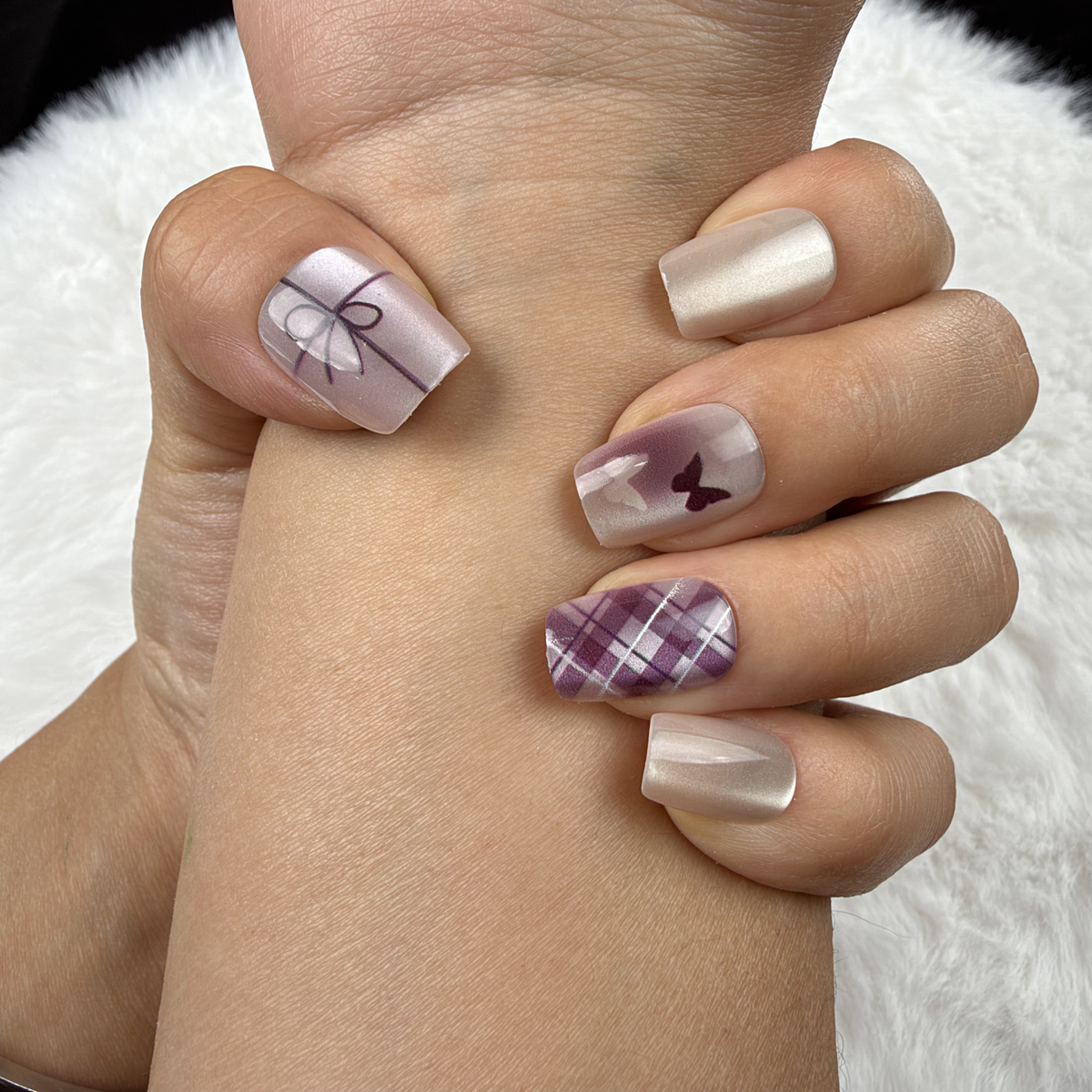 Close-up of hands wearing Ribbon Plaid pearl white and plum bow and plaid square press-on nails