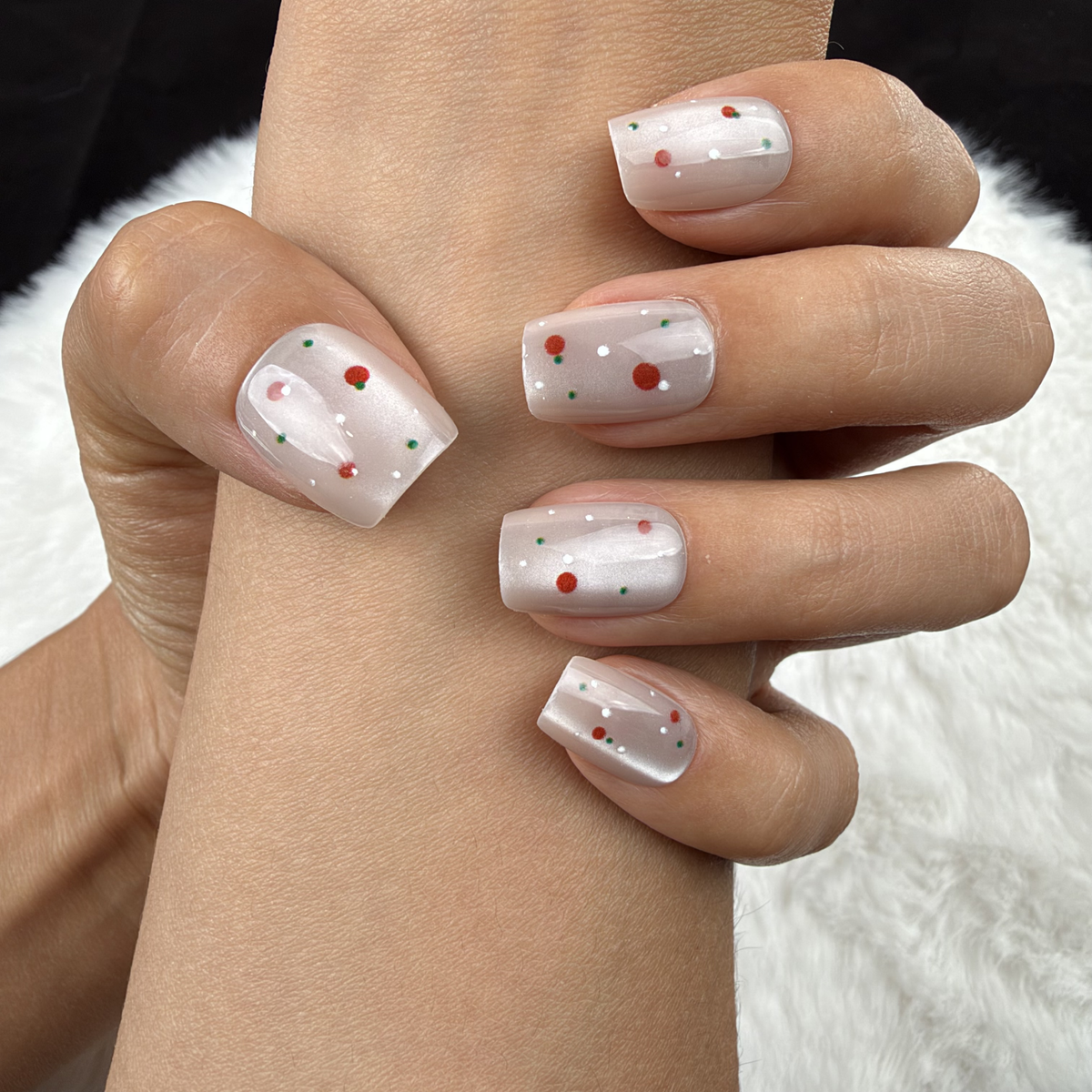 Close-up of hands wearing Cherry Pearl pearl white square press-on nails with red cherry accents