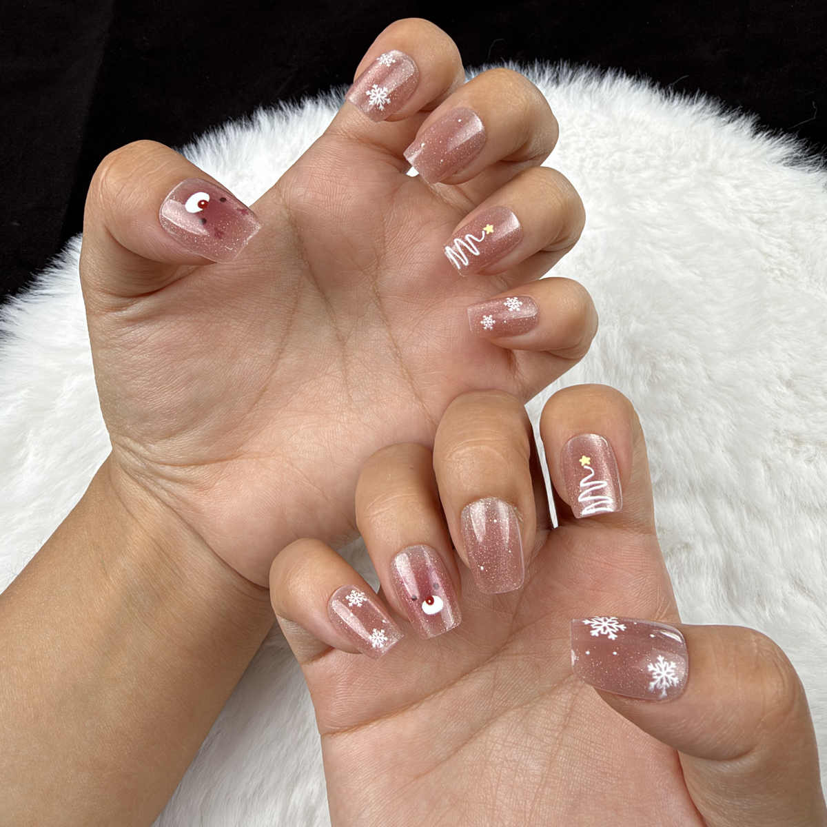 Detail shot of Reindeer Glow rose nude Christmas square press-on nails with silver reindeer and stars on hand