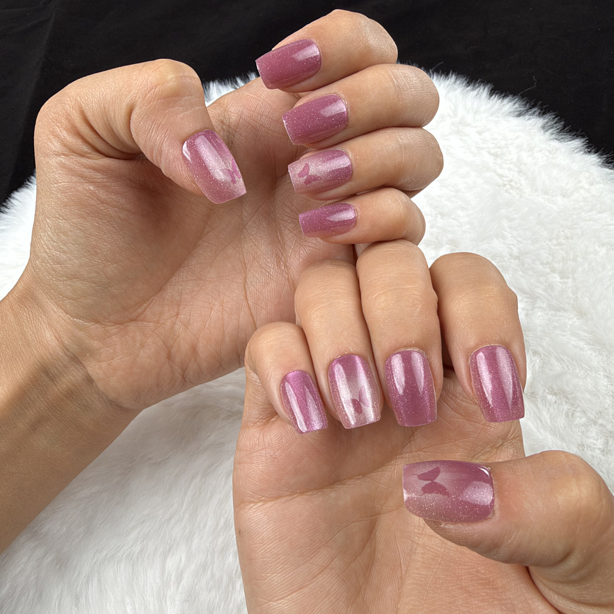 Hands wearing Rose Wings rose pink cat eye square press-on nails with butterfly accents
