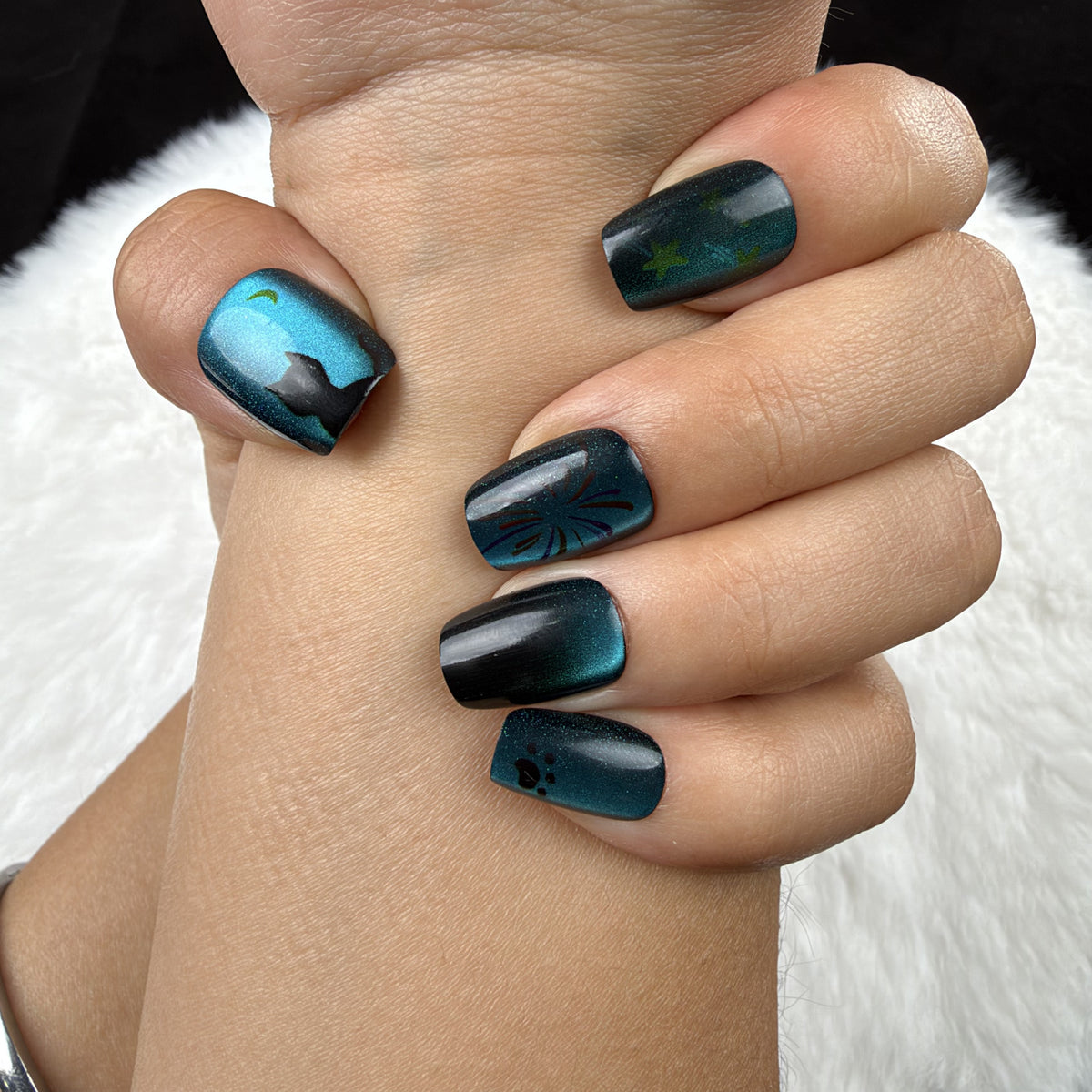 Close-up of hands wearing Ocean Afterglow teal and black cat eye square press-on nails