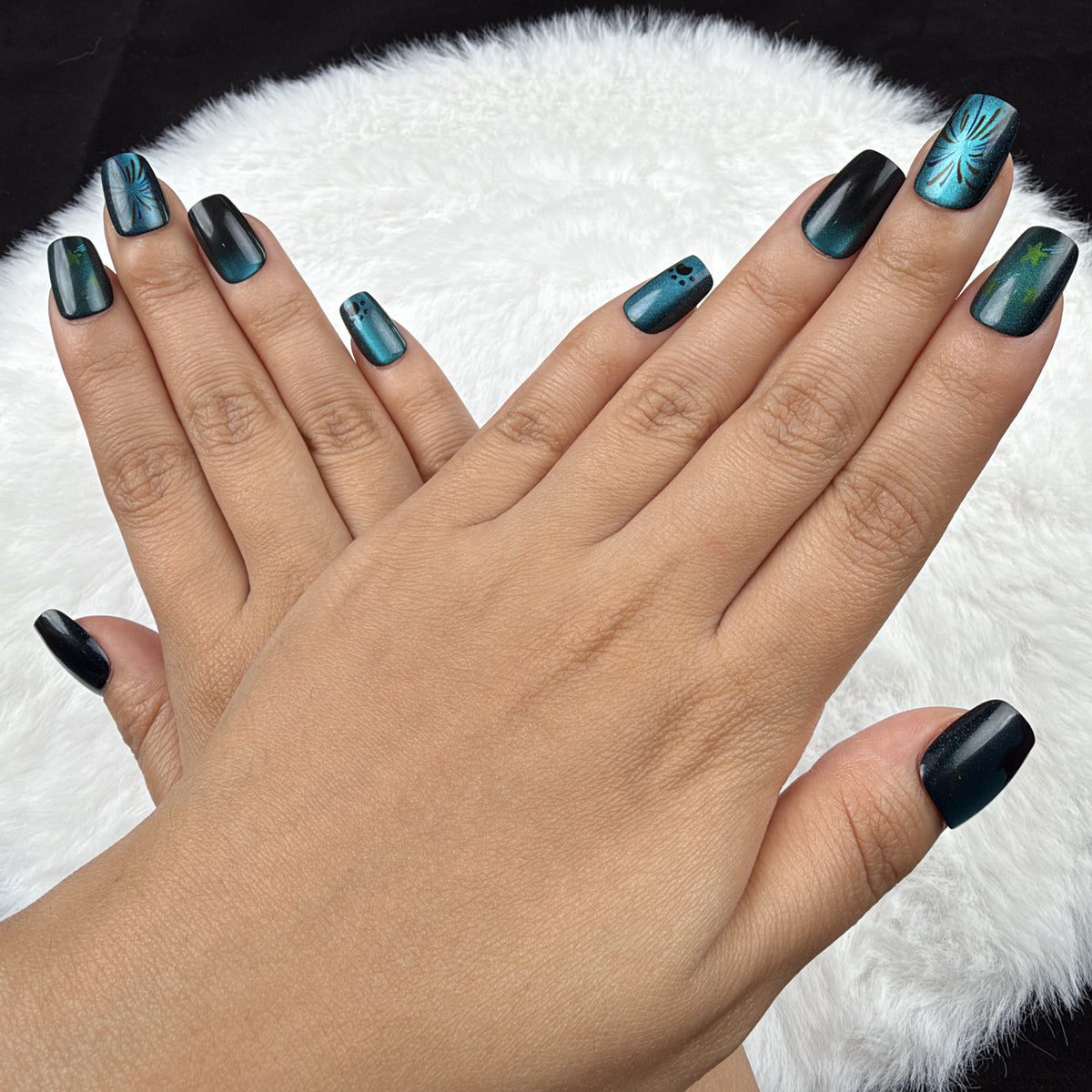 Detail shot of Ocean Afterglow teal and black cat eye square press-on nails on hand