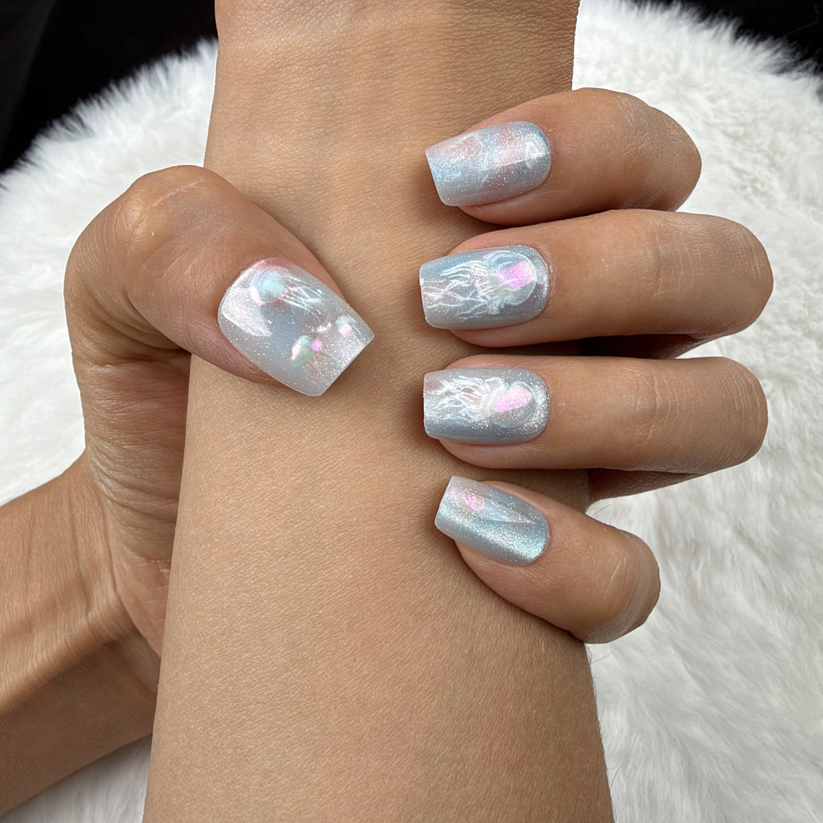 Close-up of hands wearing Jellyfish Drift blue iridescent jellyfish square press-on nails