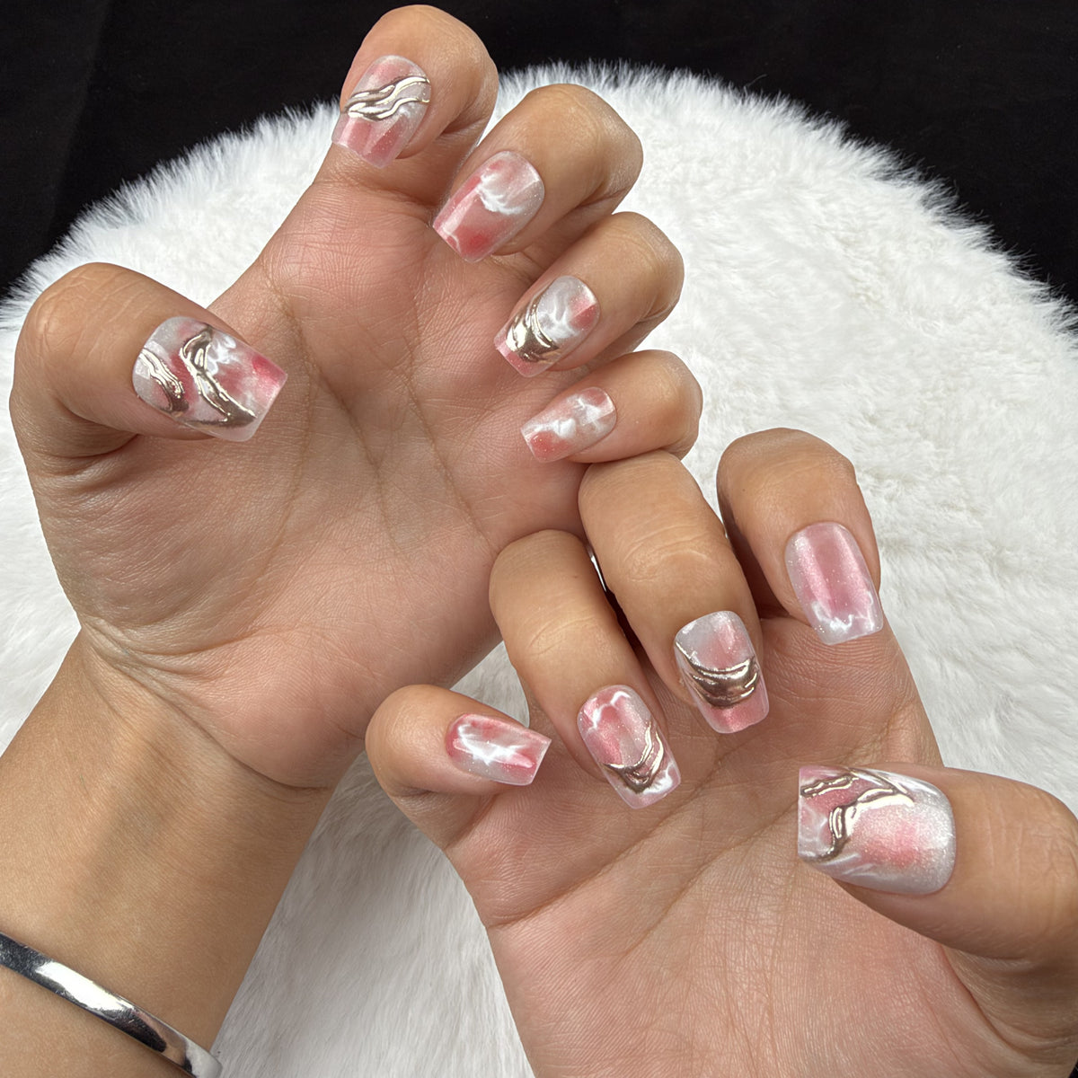 Hands wearing Rose Marble pink marble square press-on nails with metallic accents