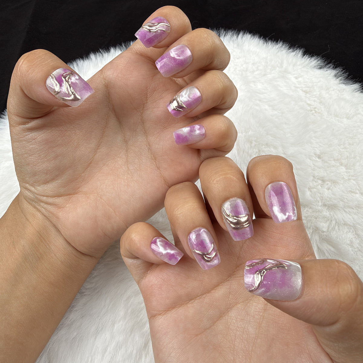 Hands wearing Orchid Marble purple marble square press-on nails with metallic accents