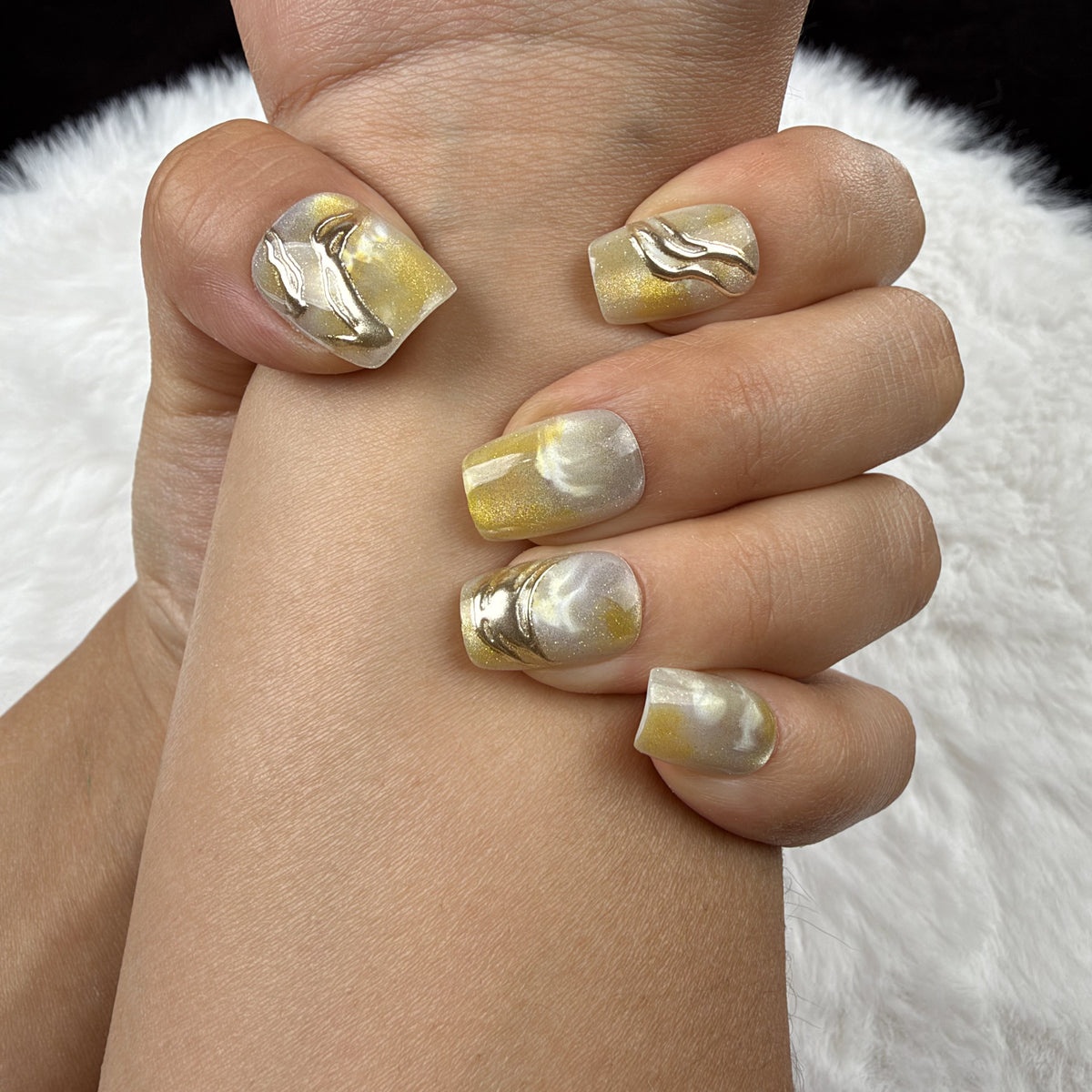 Close-up of hands wearing Citrine Marble yellow marble square press-on nails with metallic accents