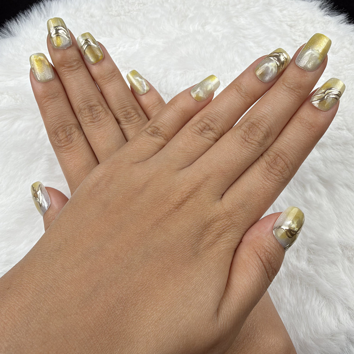 Detail shot of Citrine Marble yellow marble square press-on nails with metallic accents on hand
