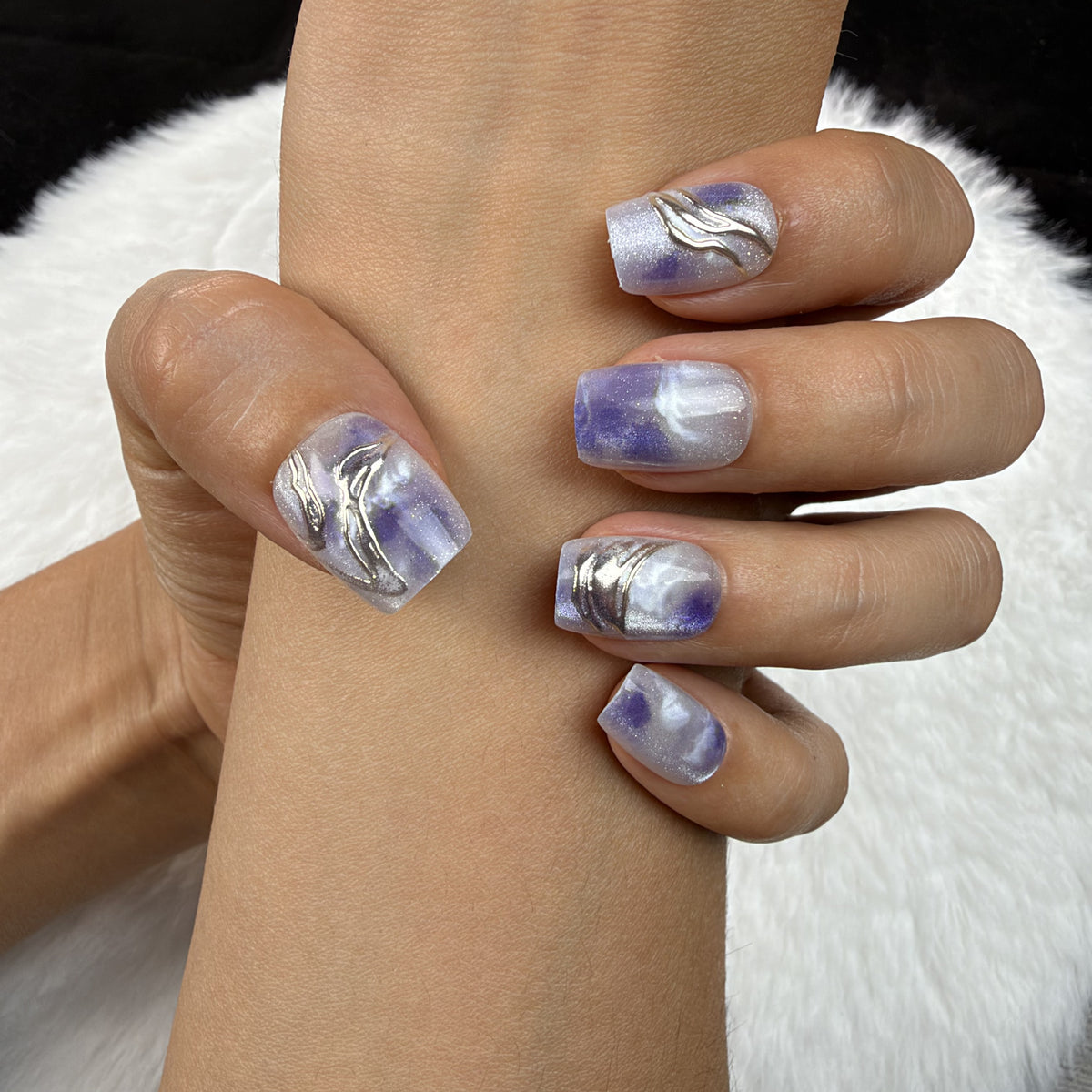 Close-up of hands wearing Violet Marble blue-violet marble square press-on nails