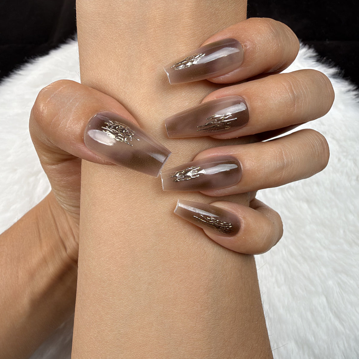Close-up of hands wearing Mocha Foil brown chrome coffin press-on nails with metallic foil accents