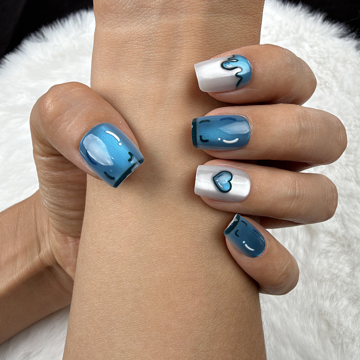 Close-up of hands wearing Blue Heart Drip blue chrome and pearl white heart square press-on nails