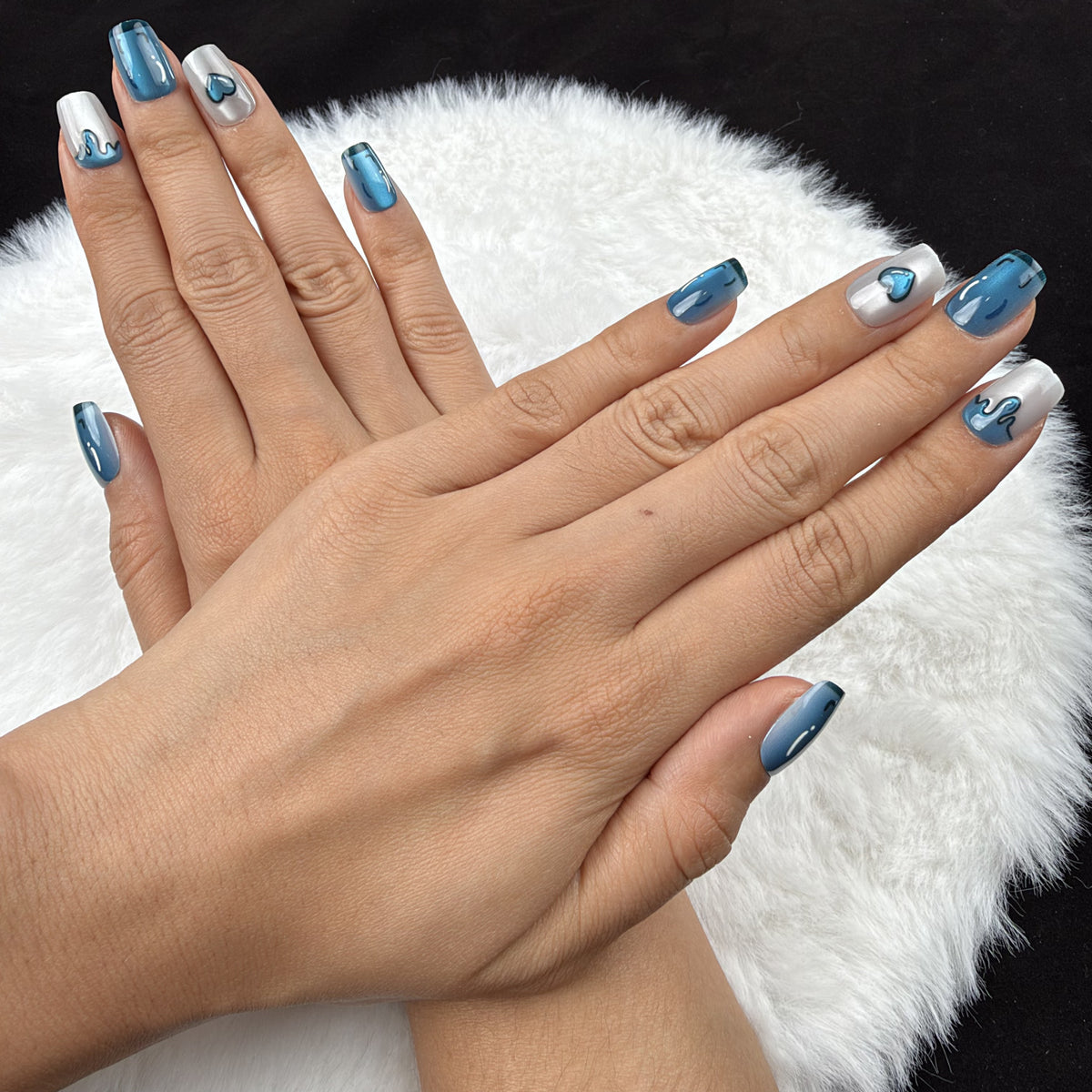 Detail shot of Blue Heart Drip blue chrome and pearl white heart square press-on nails on hand