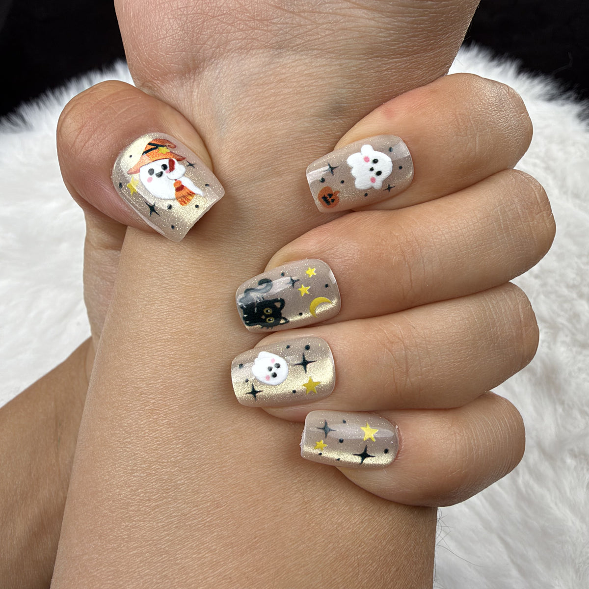 Close-up of hands wearing Spooky Confetti gold-toned ghost and pumpkin Halloween square press-on nails