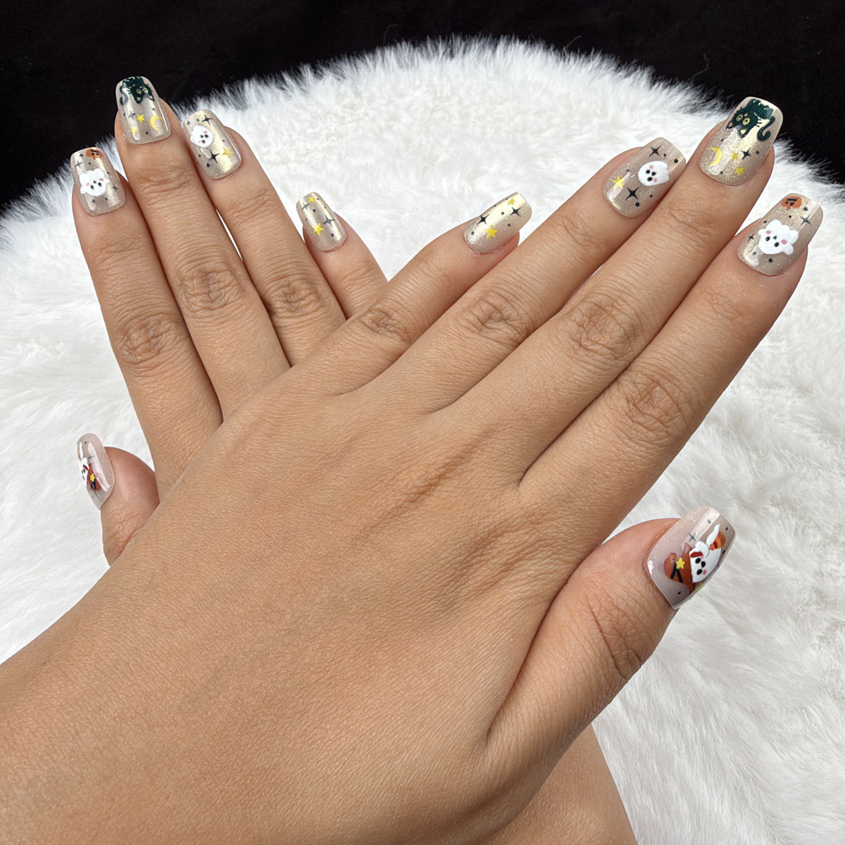 Detail shot of Spooky Confetti gold-toned ghost and pumpkin Halloween square press-on nails on hand