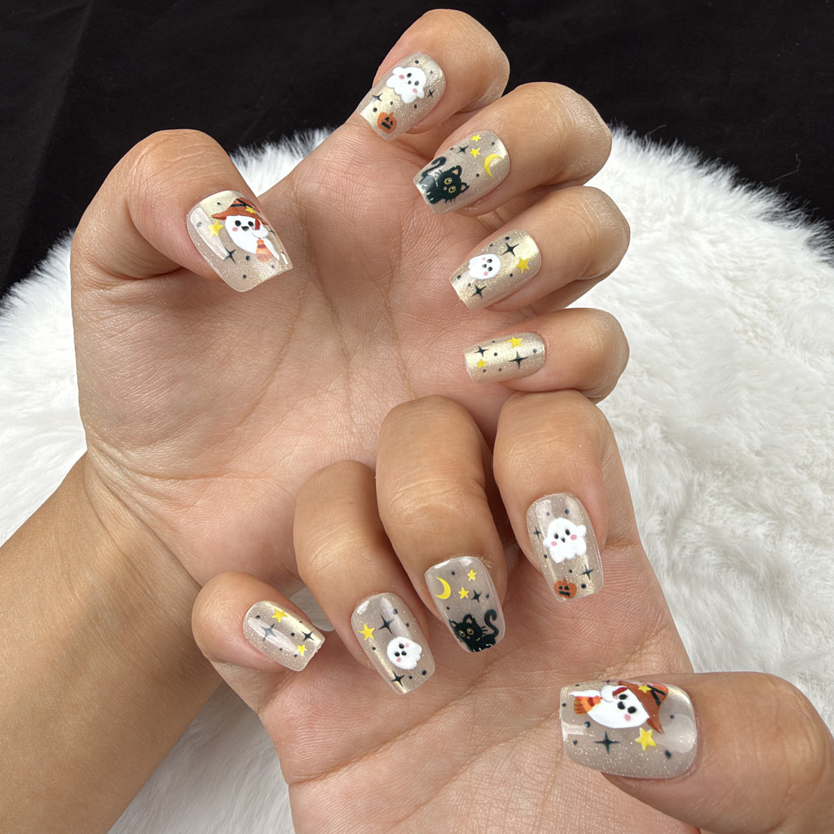 Hands wearing Spooky Confetti gold-toned ghost and pumpkin Halloween square press-on nails