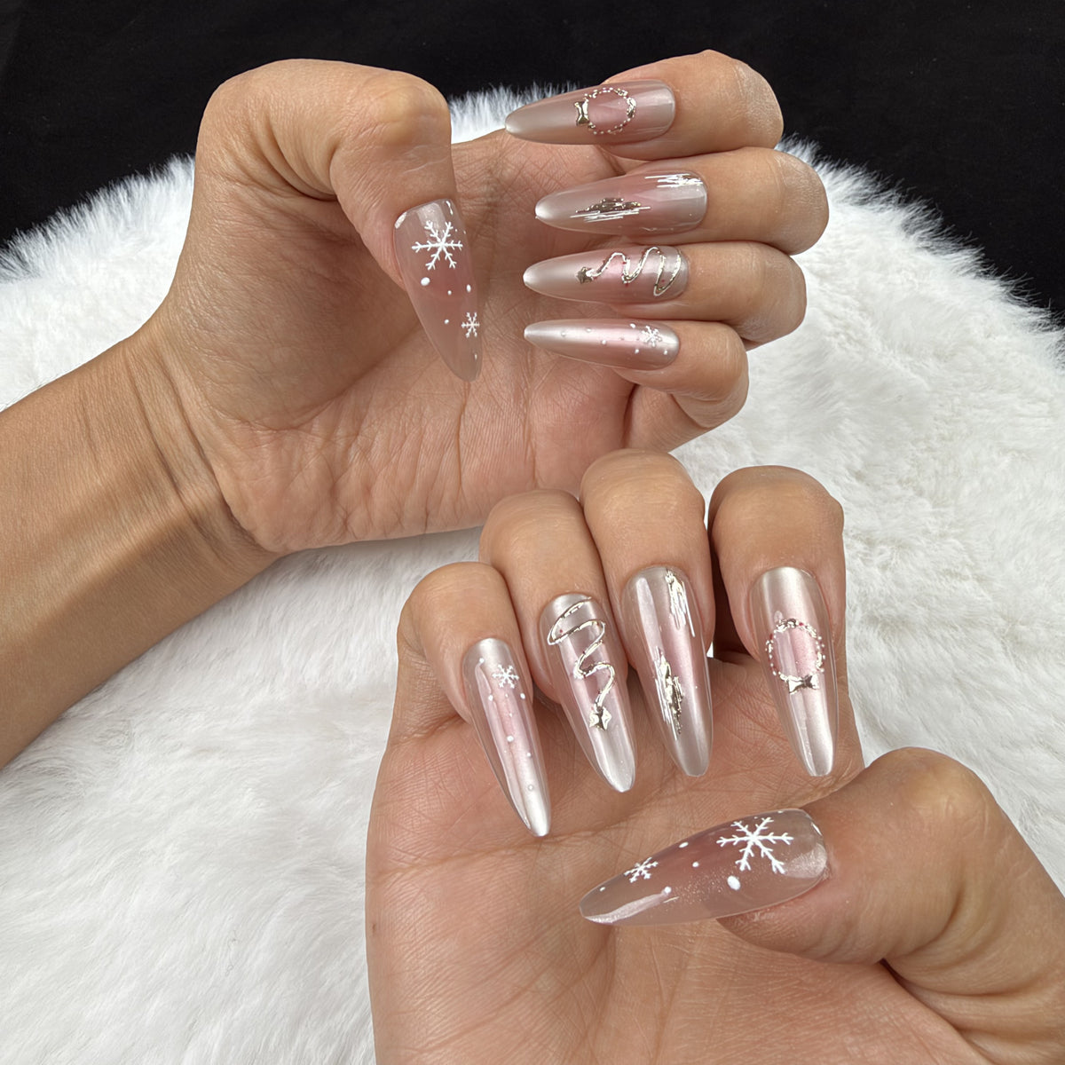 Hands wearing Winter Orbit champagne snowflake Christmas almond press-on nails