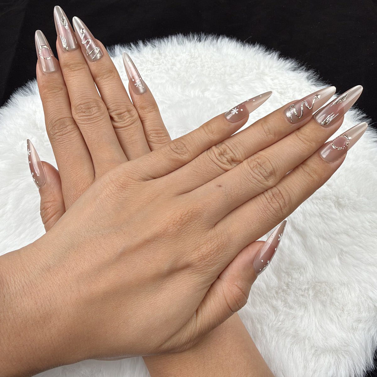 Detail shot of Winter Orbit champagne snowflake Christmas almond press-on nails on hand