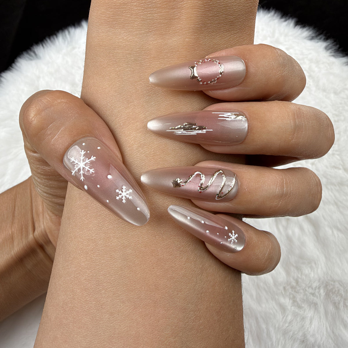 Close-up of hands wearing Winter Orbit champagne snowflake Christmas almond press-on nails