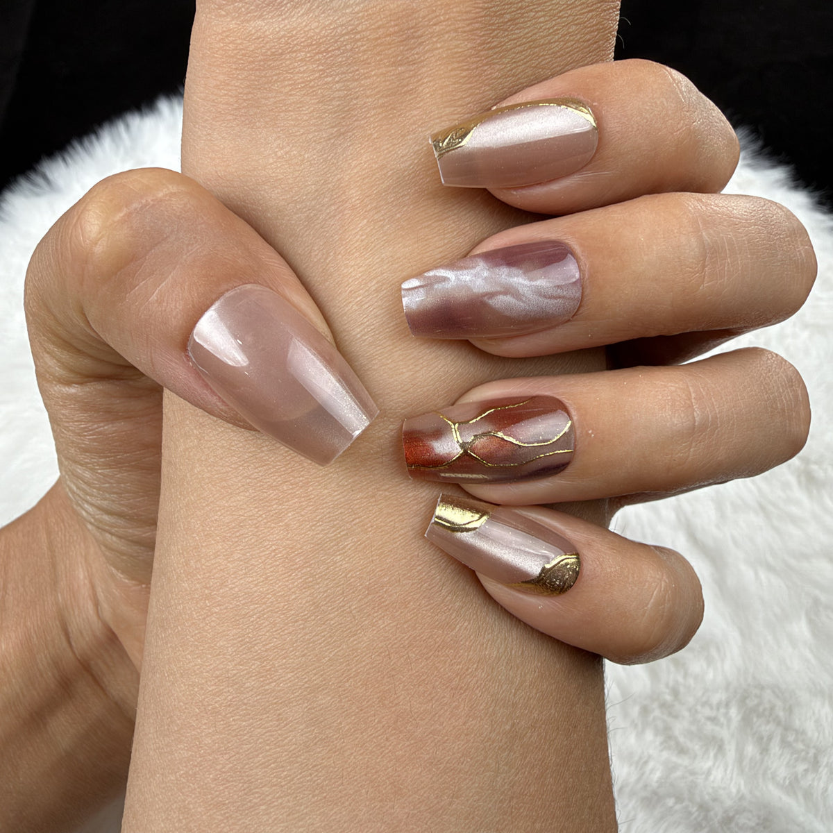 Close-up of hands wearing Amber Vein rose marble and gold-tone coffin press-on nails