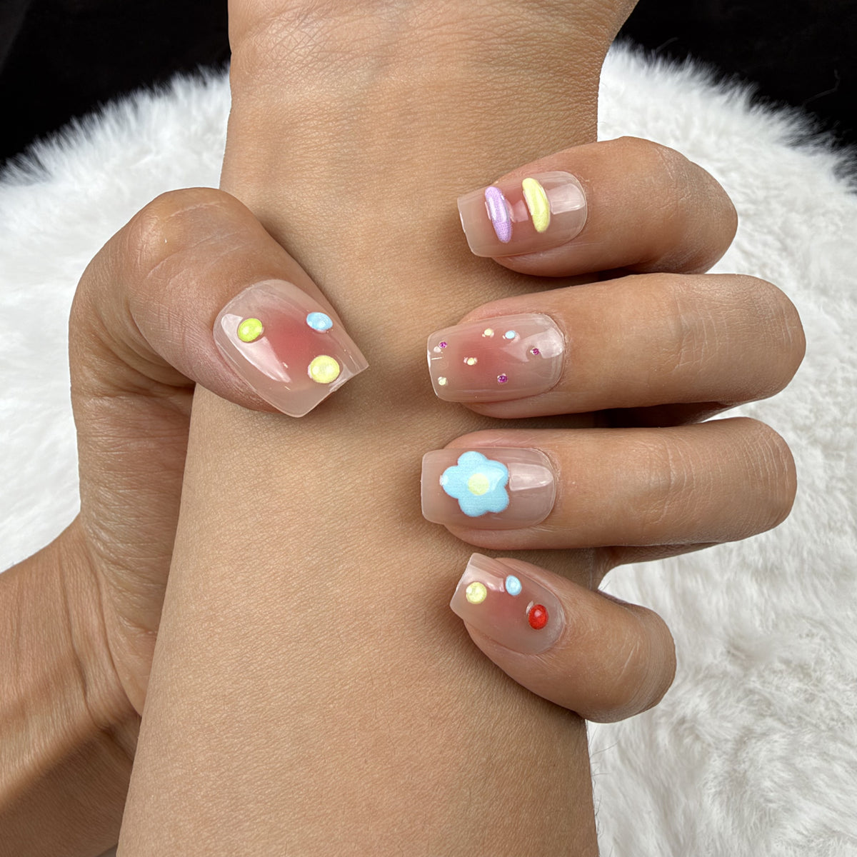 Close-up of hands wearing Candy Garden pastel square press-on nails with blue flower accents