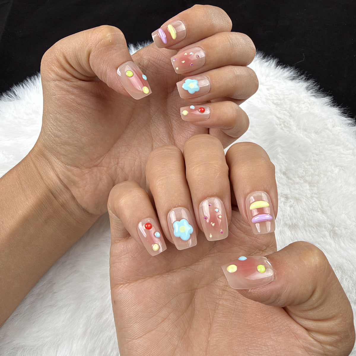 Hands wearing Candy Garden pastel square press-on nails with blue flower accents