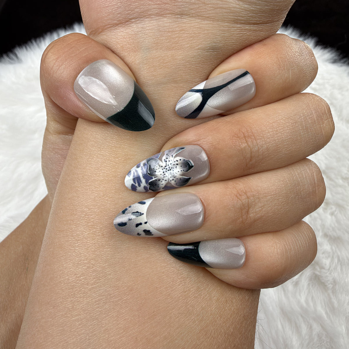 Close-up of hands wearing Midnight Iris black French tip and pearl white floral almond press-on nails