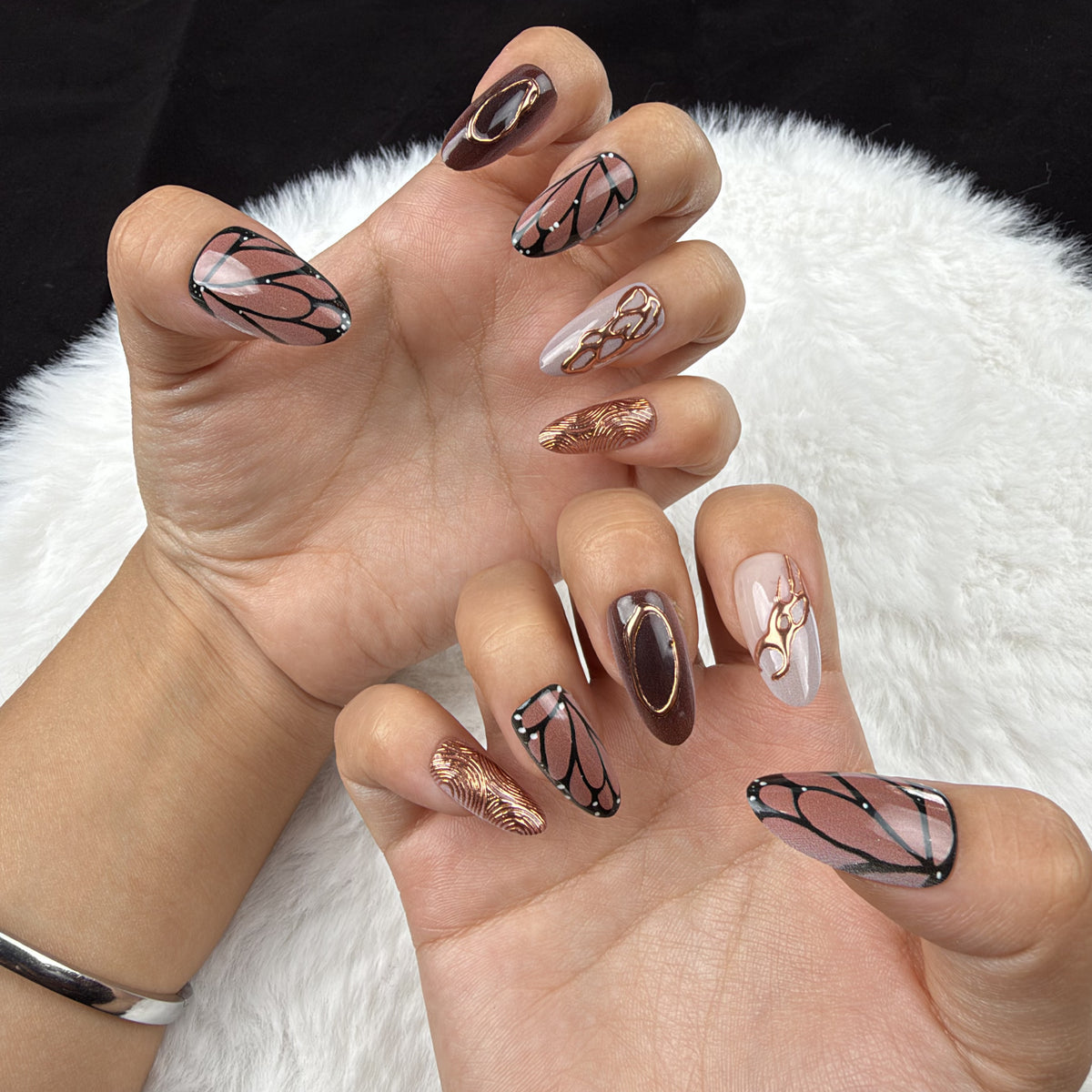 Hands wearing Copper Wings brown and copper butterfly wing almond press-on nails