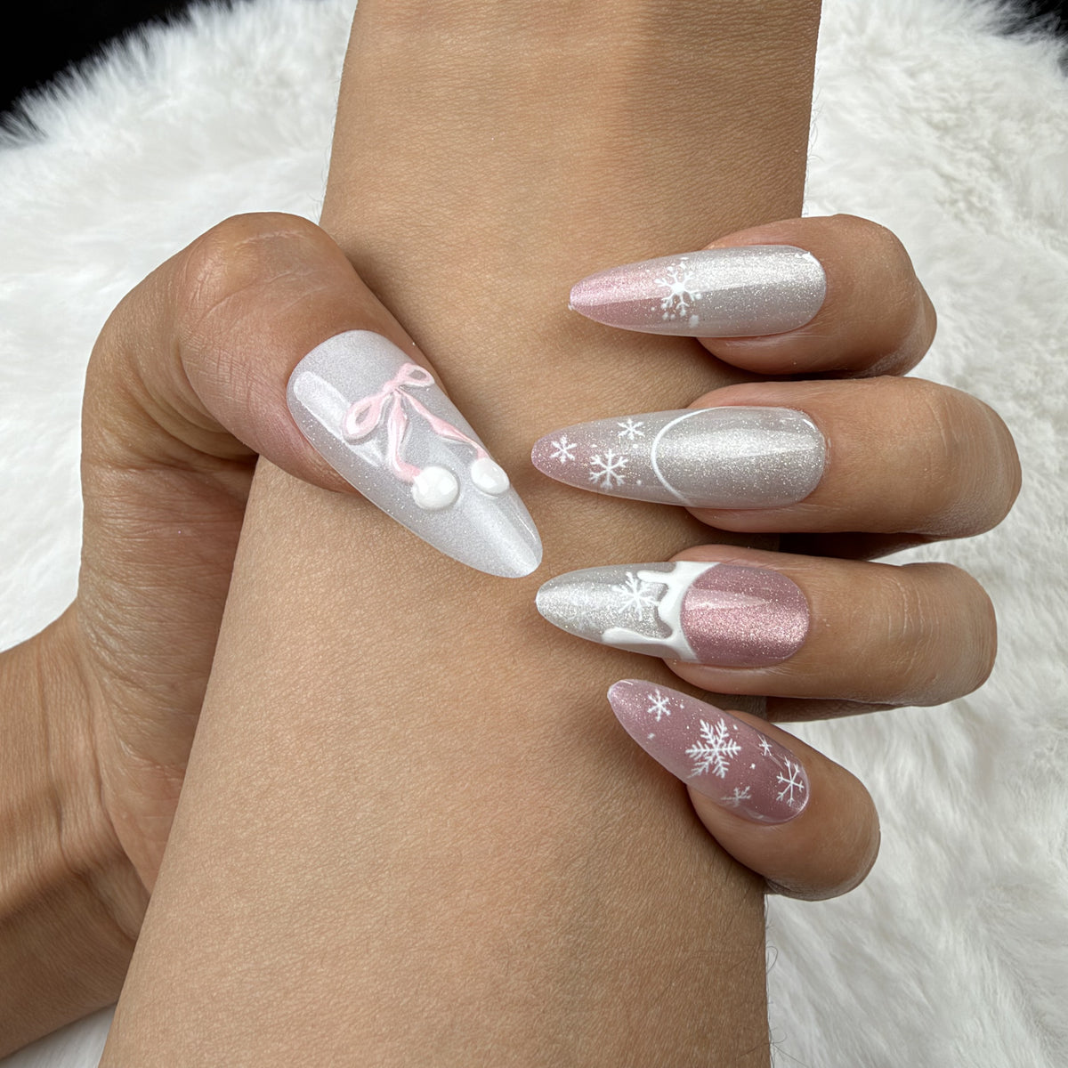 Close-up of hands wearing Snowdrop Ribbon pink and pearl white Christmas almond press-on nails