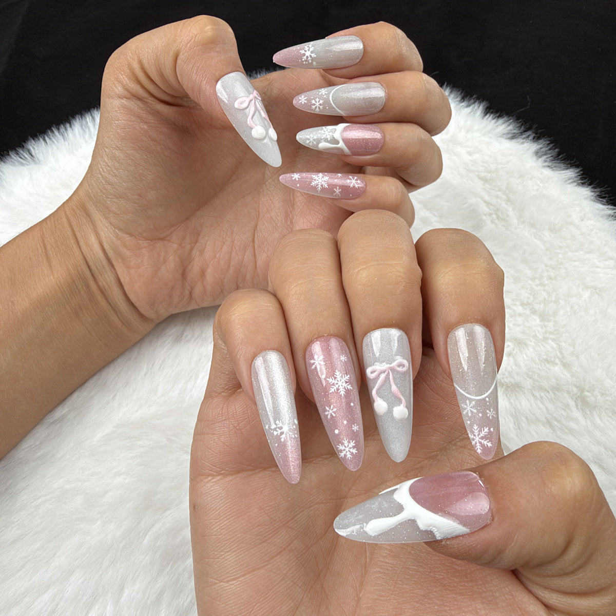 Hands wearing Snowdrop Ribbon pink and pearl white Christmas almond press-on nails