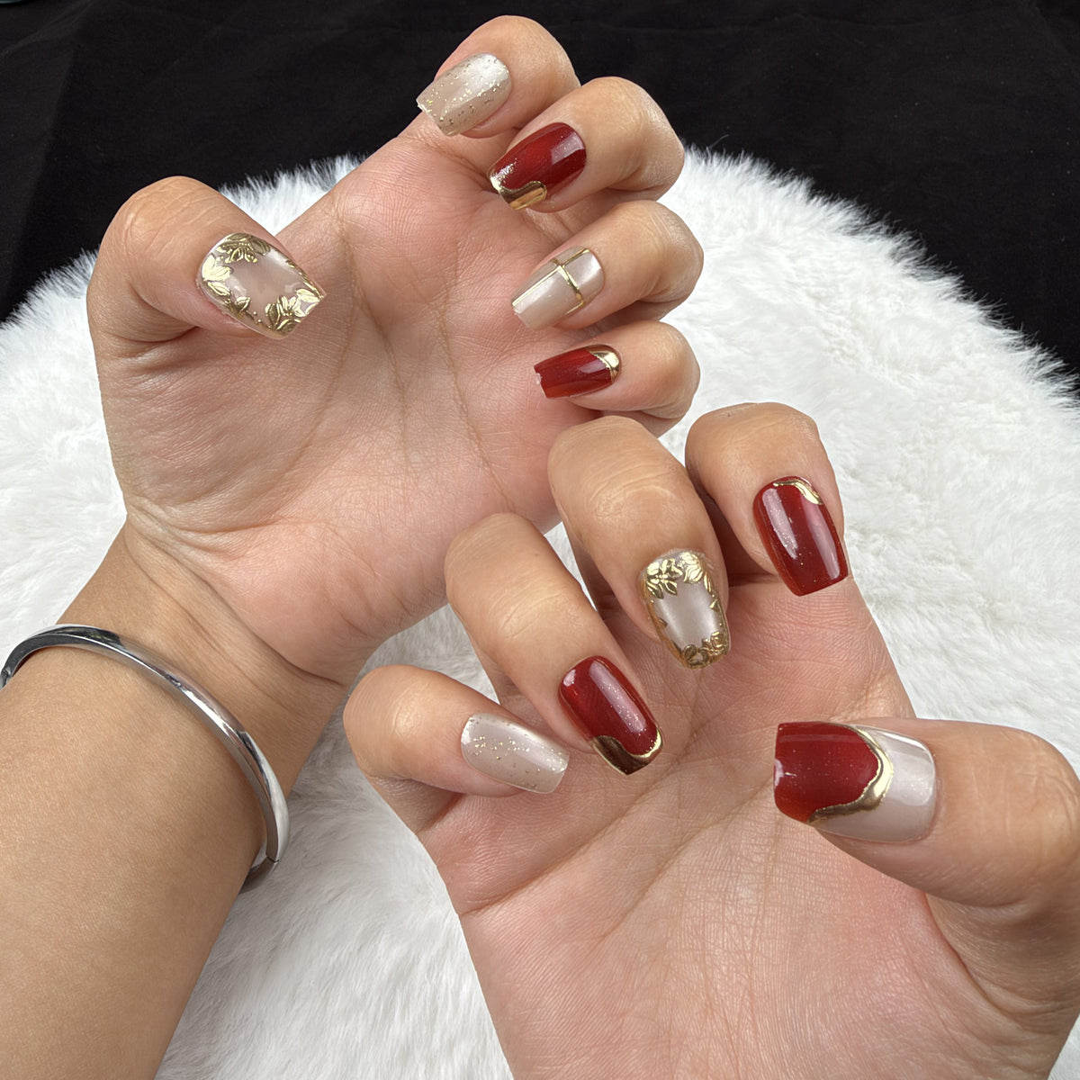 Hands wearing Crimson Frame red and gold-tone square press-on nails