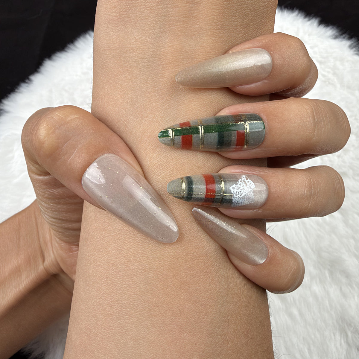 Close-up of hands wearing Cozy Plaid champagne and green plaid Christmas almond press-on nails