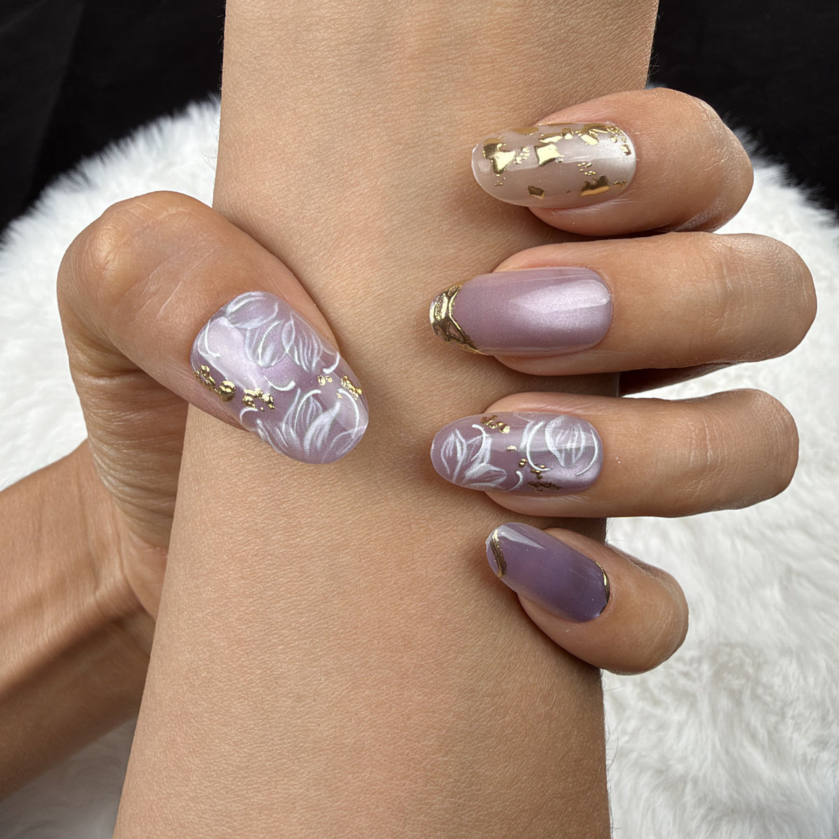 Close-up of hands wearing Lavender Vine lavender floral almond press-on nails with gold accents