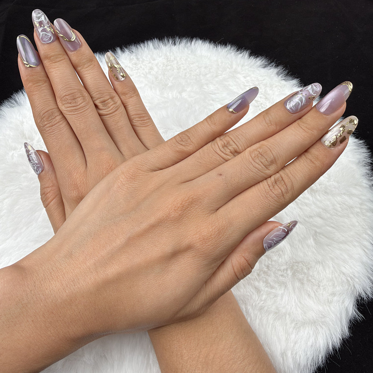 Detail shot of Lavender Vine lavender floral almond press-on nails with gold accents on hand