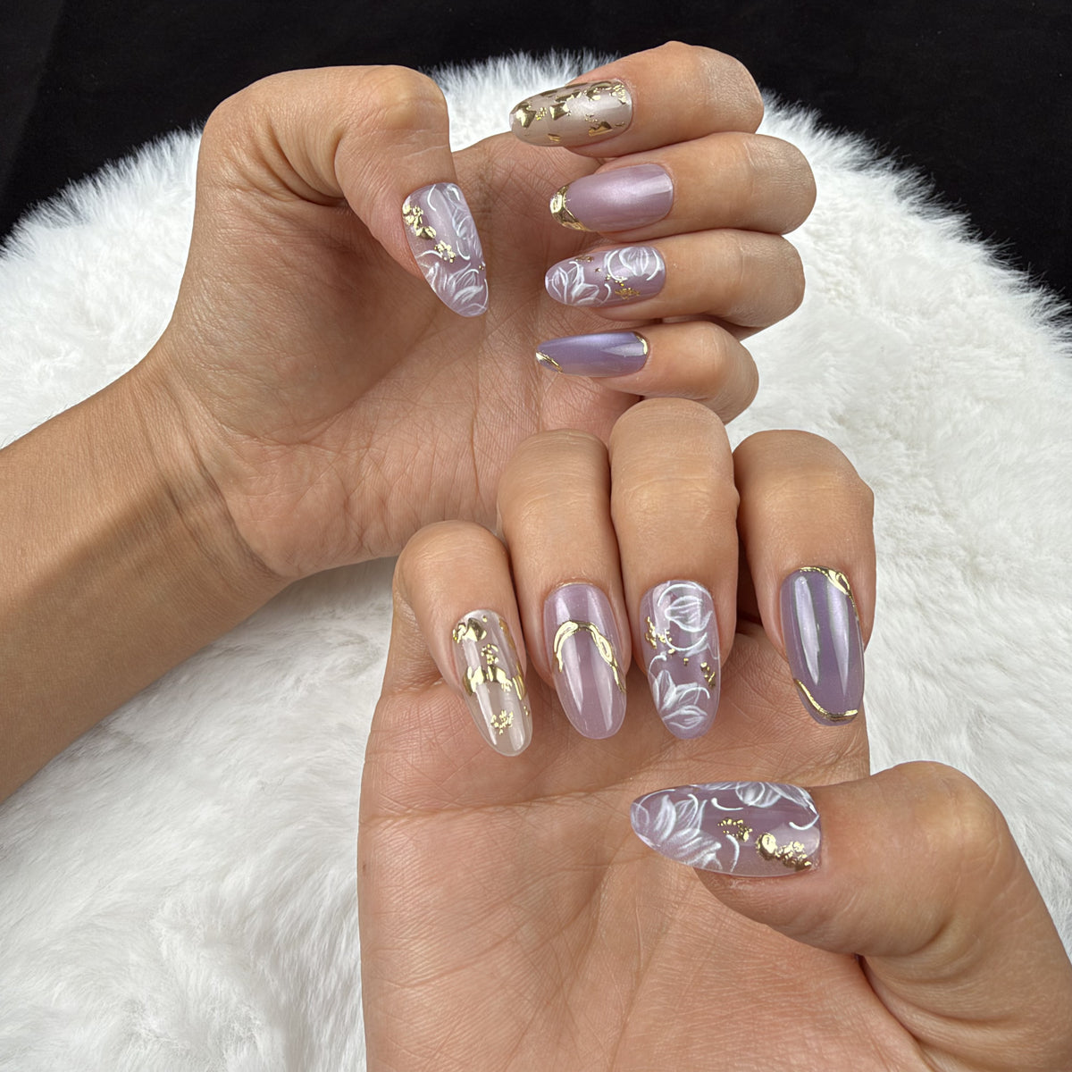 Hands wearing Lavender Vine lavender floral almond press-on nails with gold accents