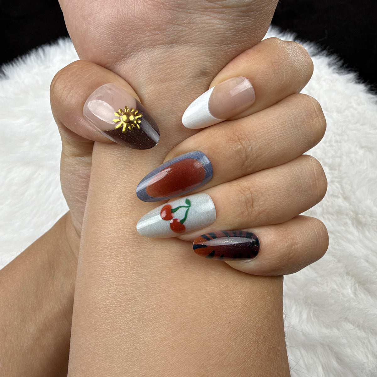 Close-up of hands wearing Autumn Picnic plaid, cherry and floral almond press-on nails