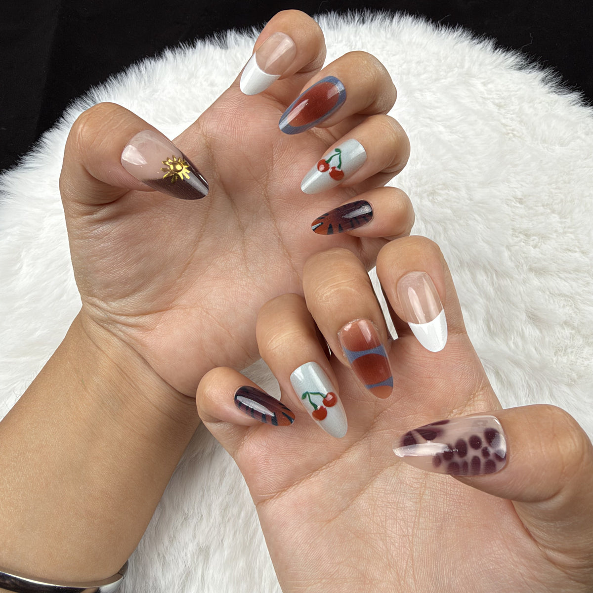 Hands wearing Autumn Picnic plaid, cherry and floral almond press-on nails