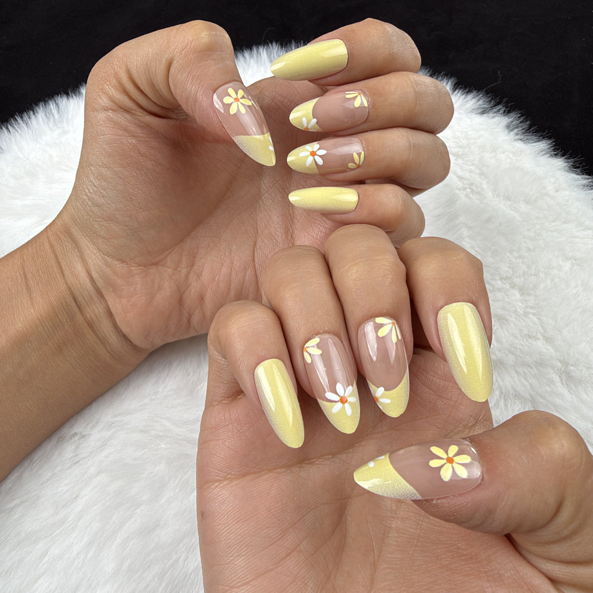 Hands wearing Sunshine Daisy yellow French tip daisy almond press-on nails