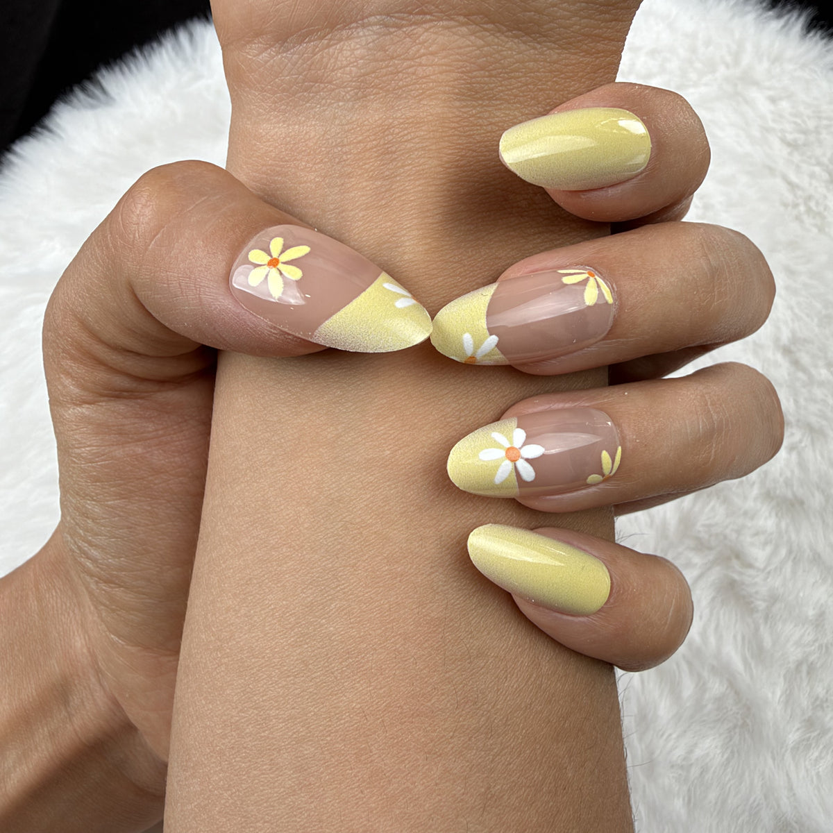 Close-up of hands wearing Sunshine Daisy yellow French tip daisy almond press-on nails