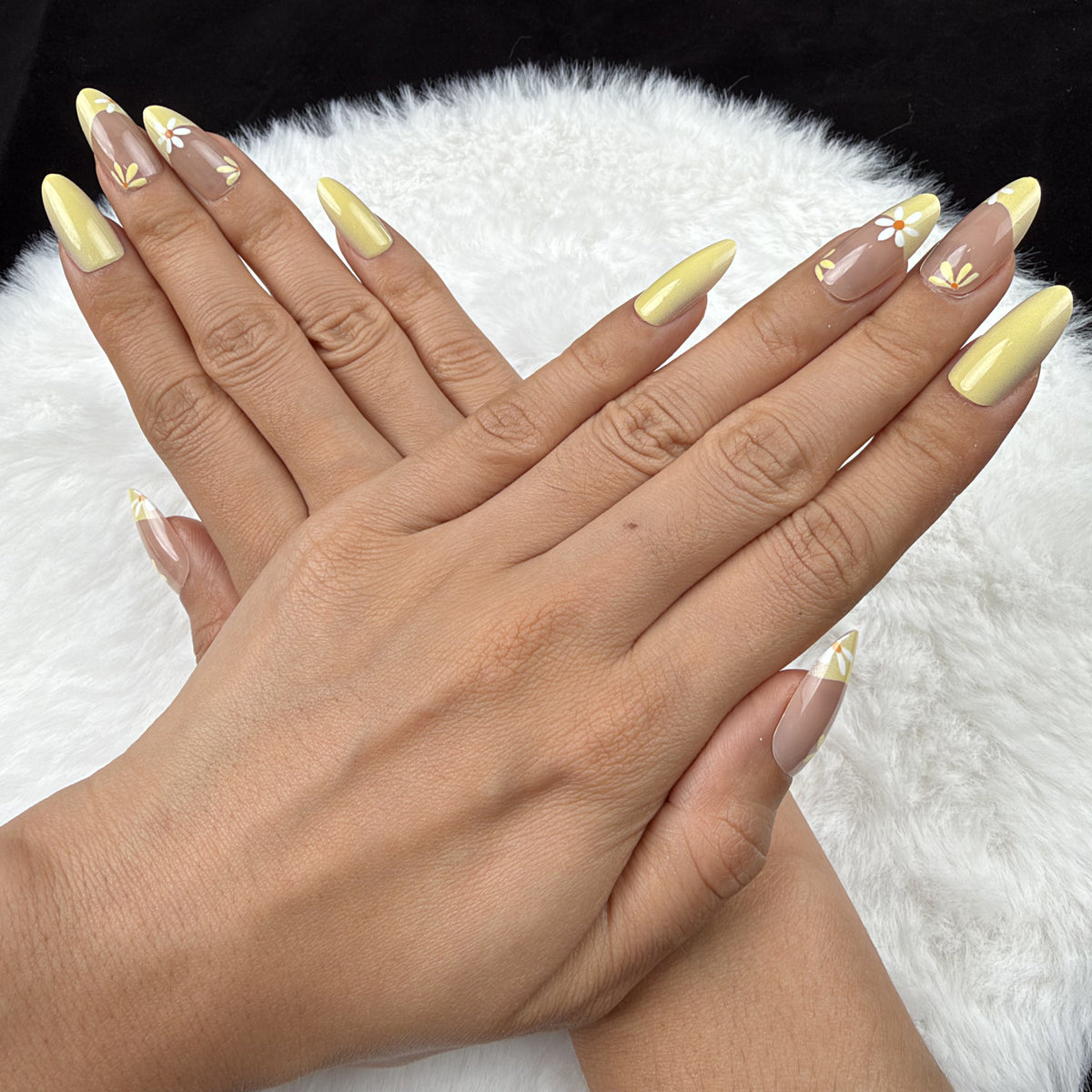 Detail shot of Sunshine Daisy yellow French tip daisy almond press-on nails on hand