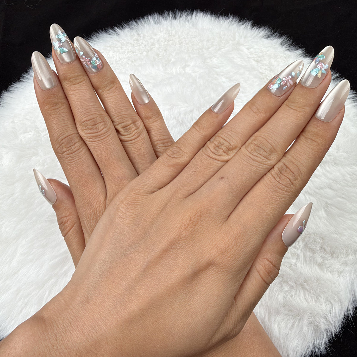 Detail shot of Opal Bouquet pearl-toned bow and floral almond press-on nails on hand