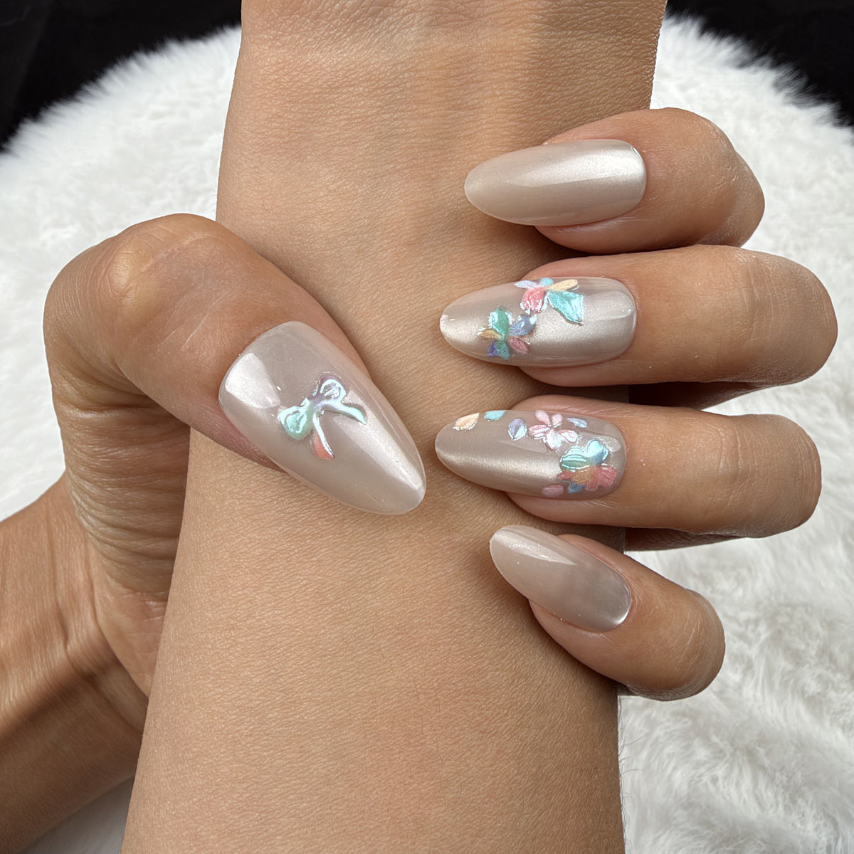 Close-up of hands wearing Opal Bouquet pearl-toned bow and floral almond press-on nails
