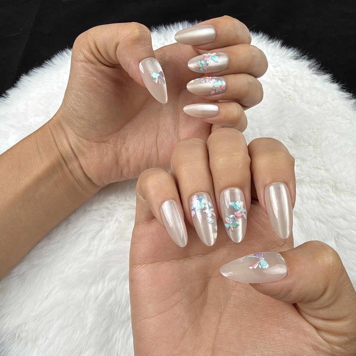 Hands wearing Opal Bouquet pearl-toned bow and floral almond press-on nails