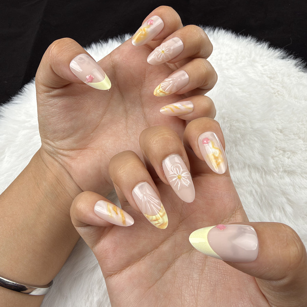 Hands wearing Honey Meadow yellow marble and floral almond press-on nails