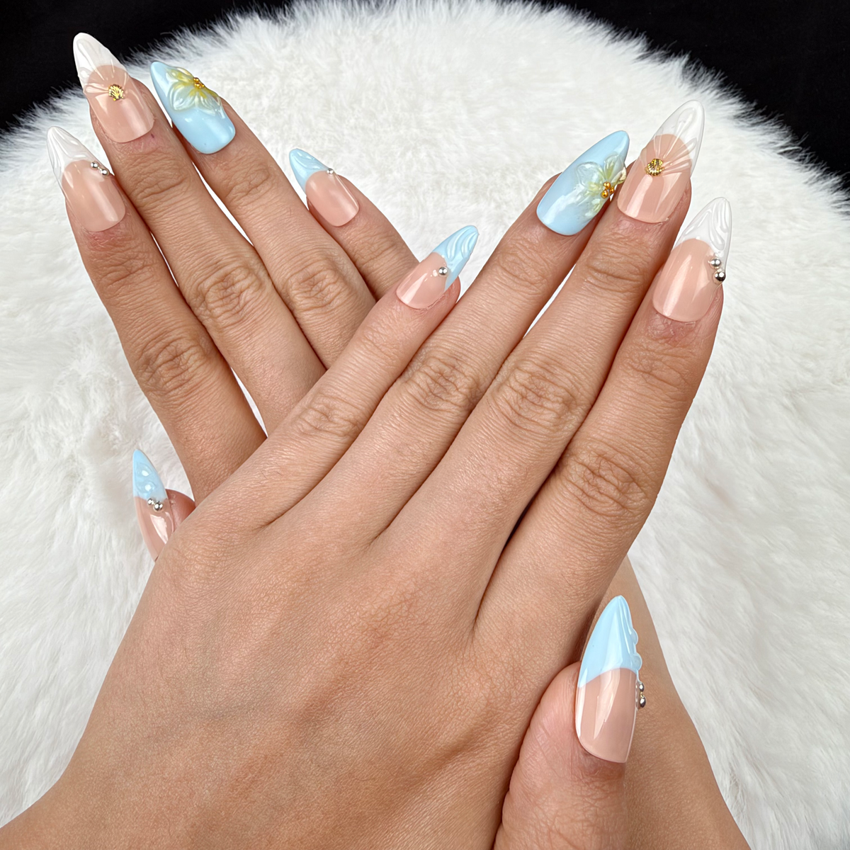 Hands wearing Seaside Petals light blue and nude shell floral almond press-on nails