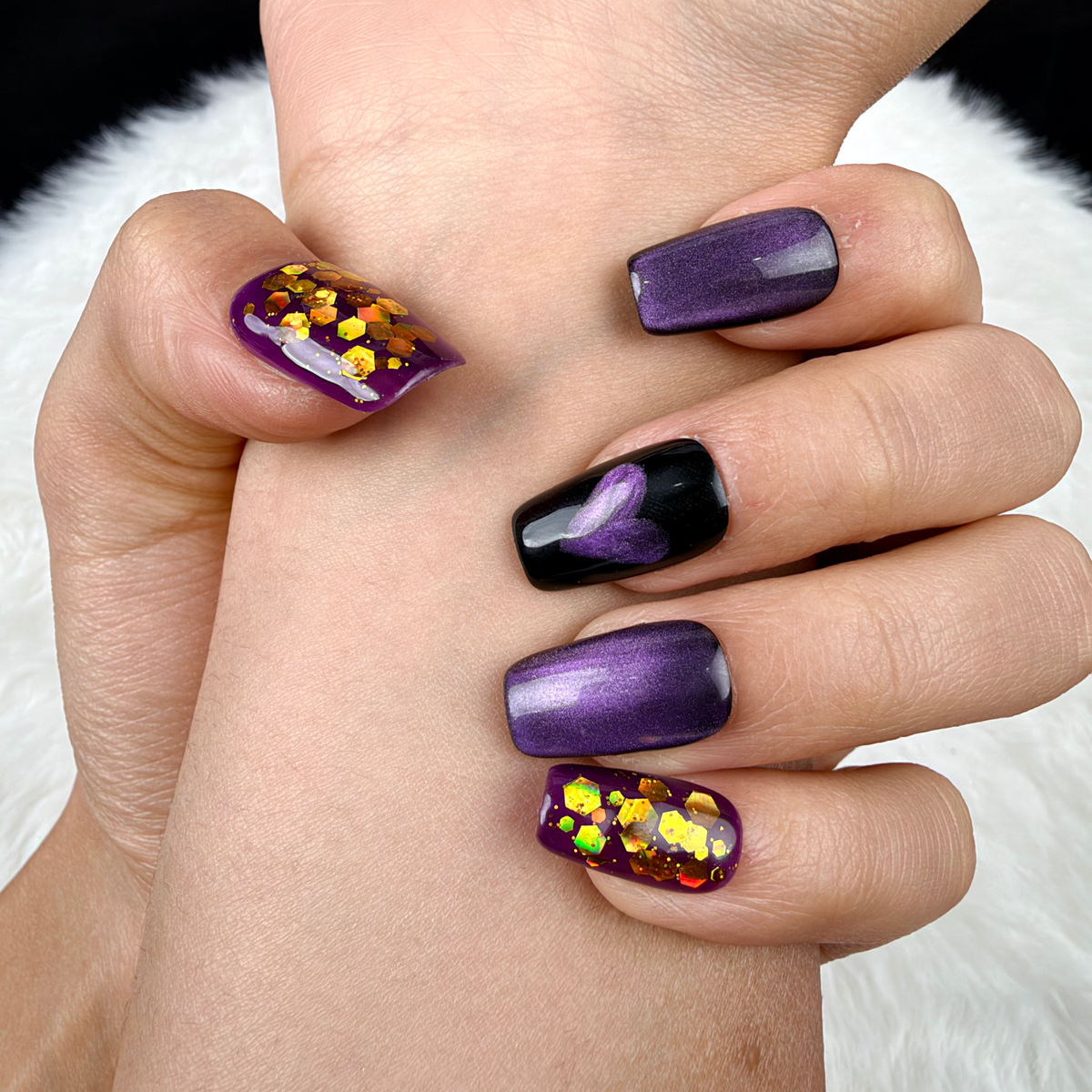 Detail shot of Purple Hearts purple cat eye and gold glitter heart square press-on nails on hand
