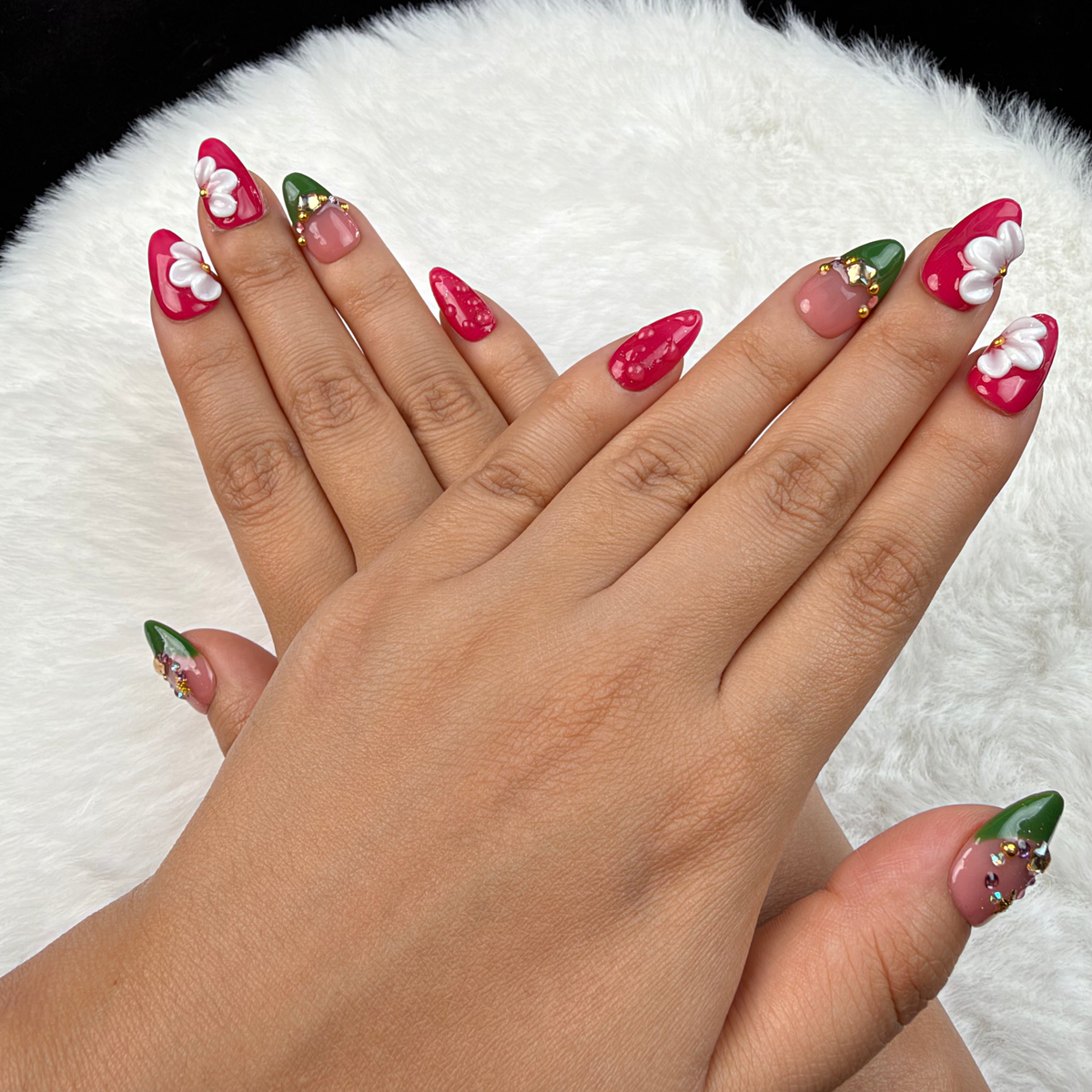 Detail shot of Holly Petals green and berry red Christmas floral almond press-on nails on hand