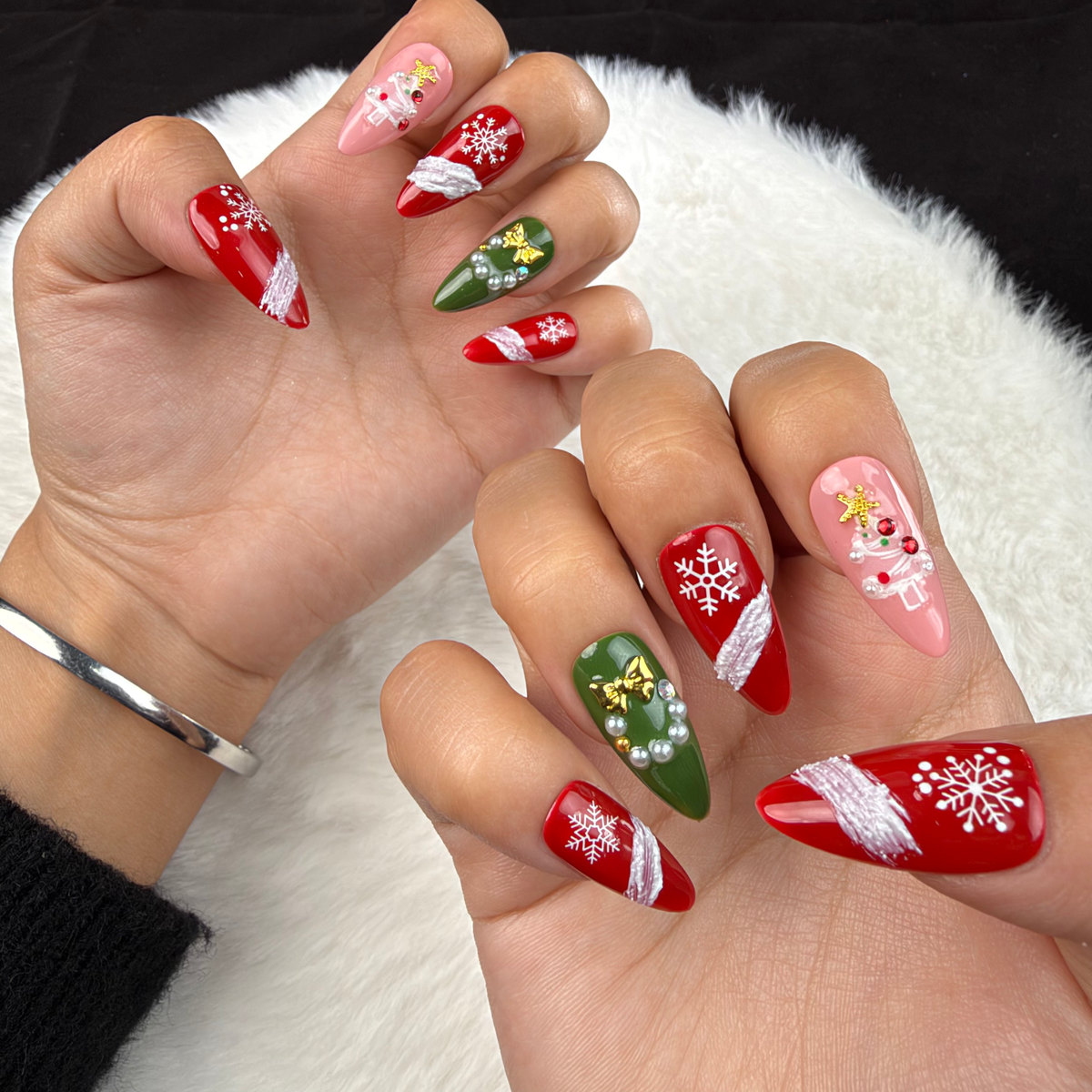 Hands wearing Evergreen Ribbon red, pink and green snowflake Christmas almond press-on nails