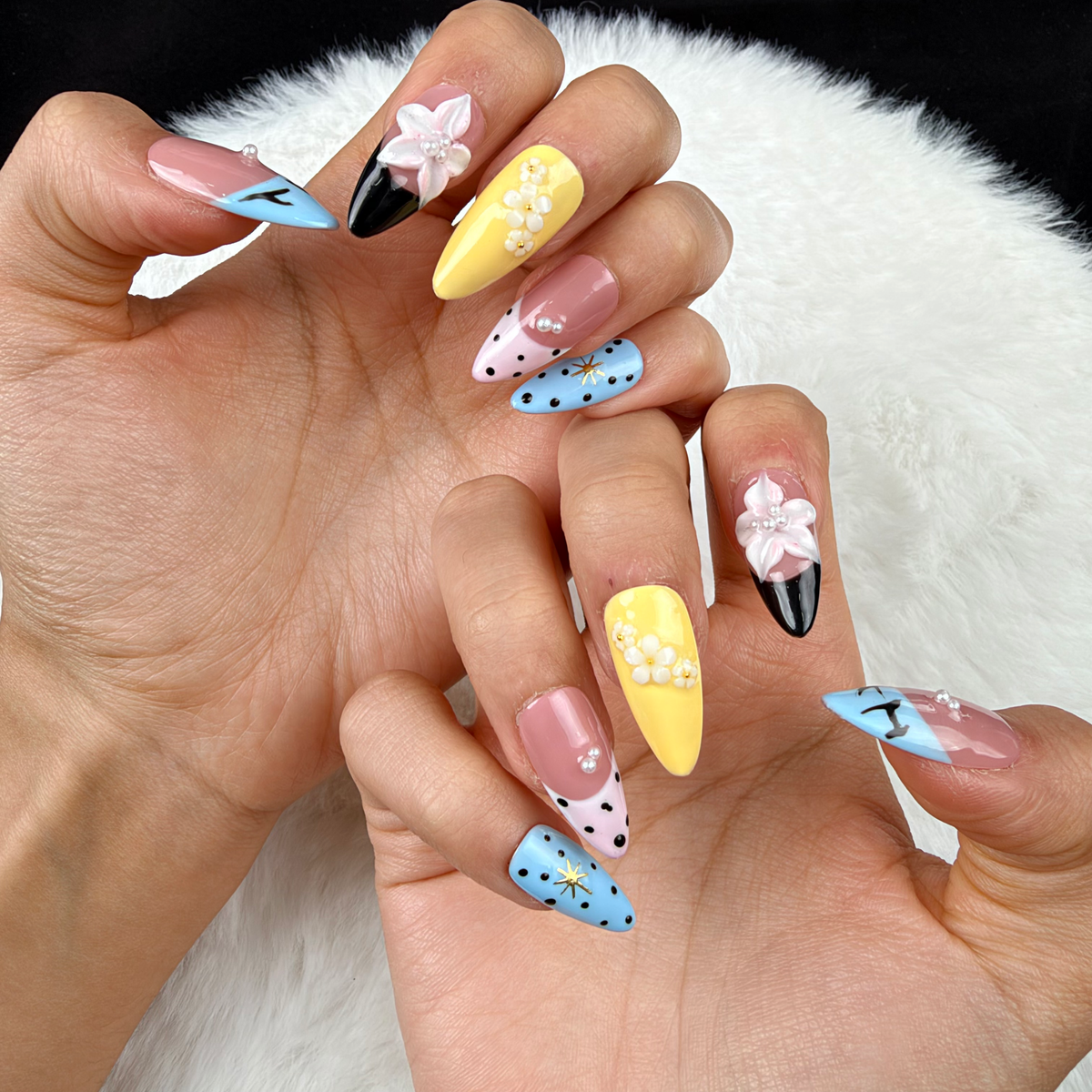 Close-up of hands wearing Pastel Graphic Garden blue, yellow and pink floral almond press-on nails